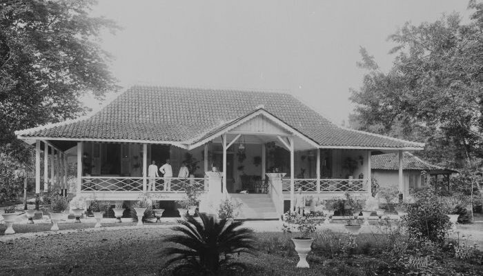 Een dokter op de veranda van de dokterswoning met tuin in Soebang 1900 - 1940